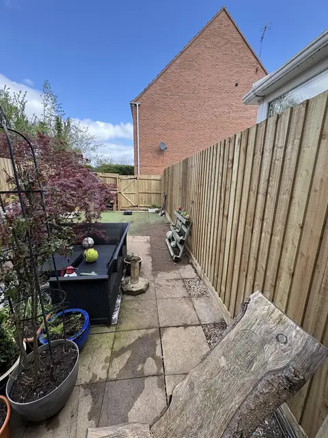 A new fence panel run along the side of a paved garden