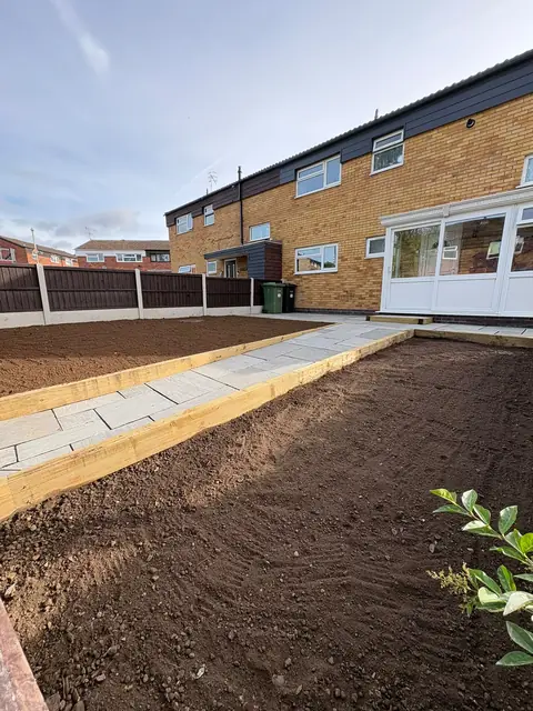 A curved paved border with fresh topsoil laid behind it
