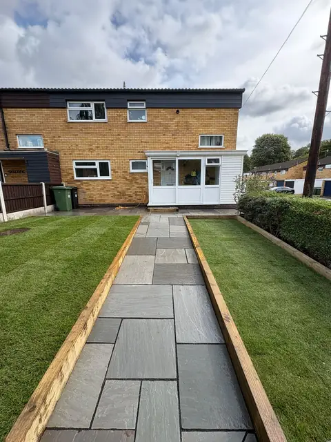 A slab path down the middle of a garden with lawn either side