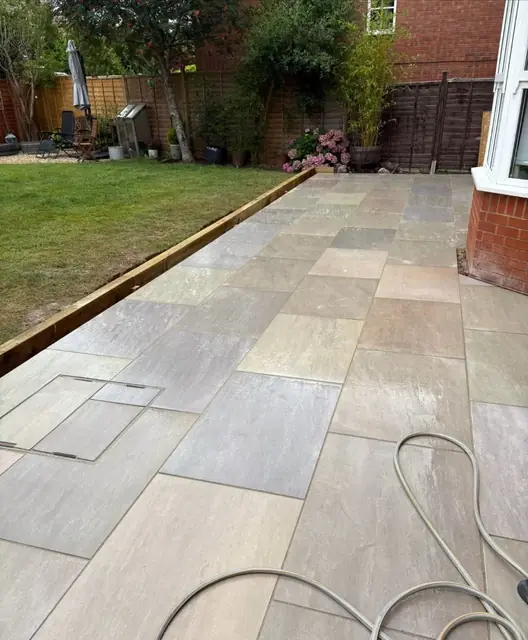 A grey slab path opening out into a patio area